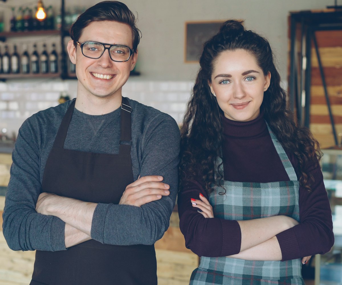 Deux commerçants souriants devant leur comptoir